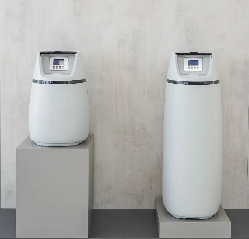 Zwei moderne Wasserenthärtungsgeräte der Marke Aqua Global stehen auf grauen Podesten vor einer minimalistischen, hellen Wand mit dem beleuchteten Logo "aqua-global".